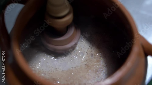 Shaking hot cocoa in a clay pot with Mexican molinillo