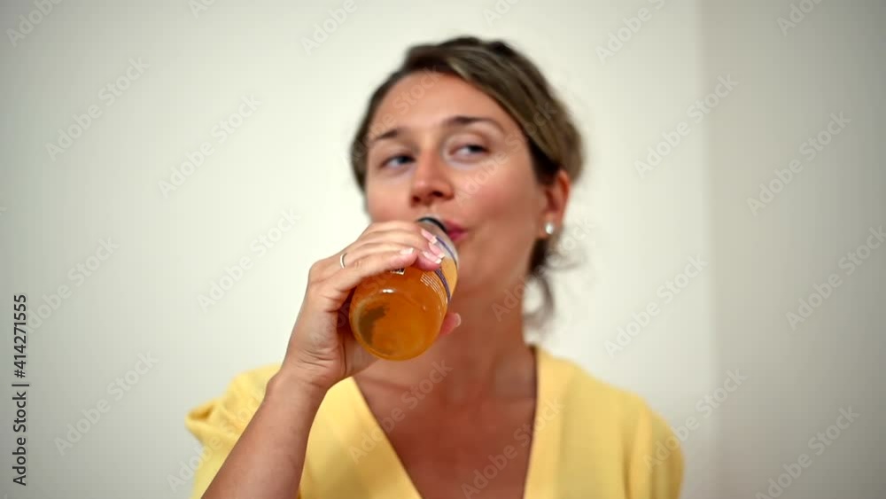 Woman wearing yellow dress opening and drinking kombutcha green tea Woman wearing yellow dress opening and drinking kombutcha green tea