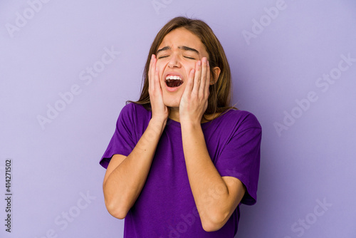 Young skinny caucasian girl teenager on purple background whining and crying disconsolately.