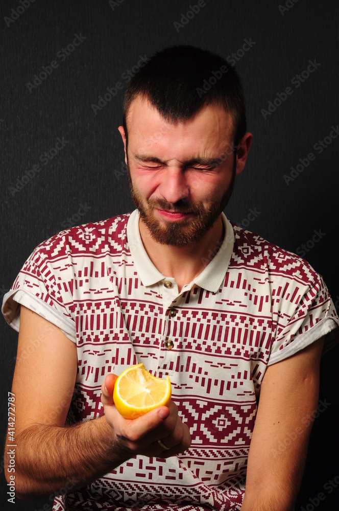Fototapeta premium a guy with a beard eating lemon