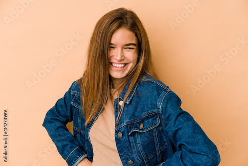 Young skinny caucasian teenager girl laughs happily and has fun keeping hands on stomach.