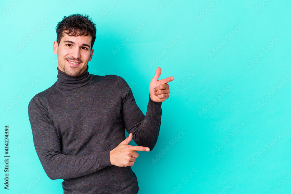 Young caucasian man isolated on blue background pointing with forefingers to a copy space, expressing excitement and desire. Young caucasian man isolated on blue background pointing with forefingers to a copy space, expressing excitement and desire.