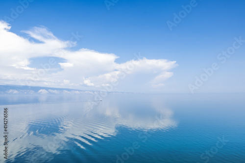 A beautiful cloud is reflected on the calm surface of the water. A boat sails in the distance. Copy space.