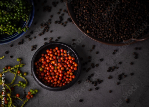 selective focus,red pepper in black cup on dark background,with black pepper background