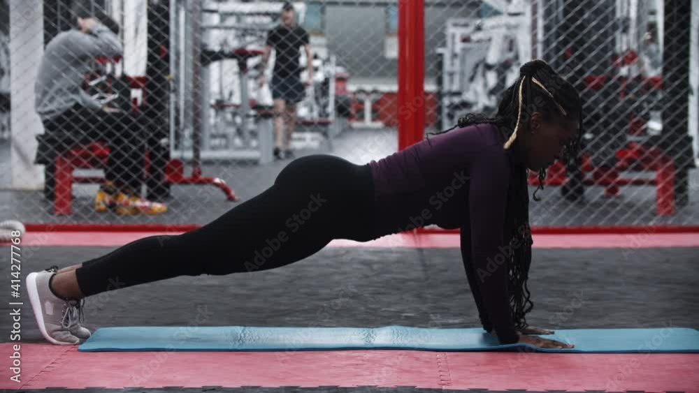 An african-american woman doing push ups and falls down