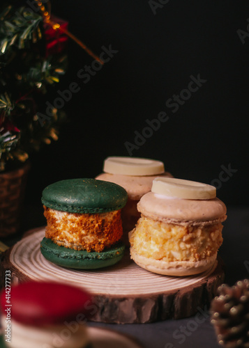 white macaroon,green macaroon on the wood plate with christmas tree on dark background