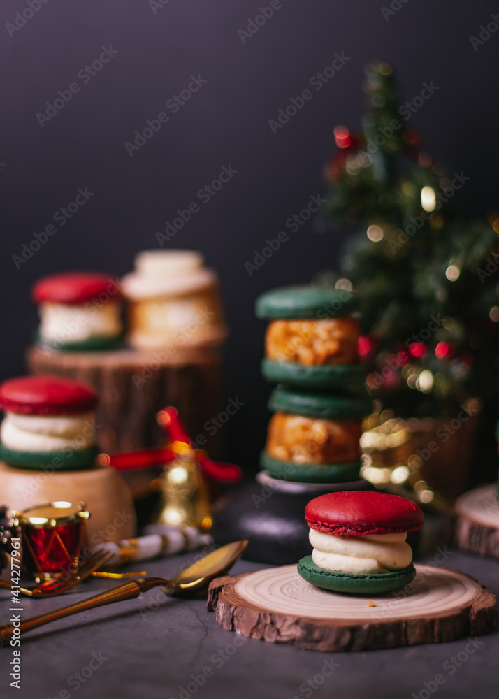 red macaroon,white macaroon,green macaroon on the wood plate with christmas tree on dark background
