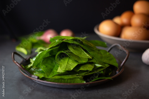 ingredient for Stir-fried Malindjo leaves with Egg on dark background. (Thai name is Bai Lieng Pad Kai),the leaves is local plant of Southern Thailand, believe it is healthy food photo