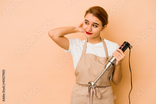 Young skinny arab cook woman touching back of head, thinking and making a choice.