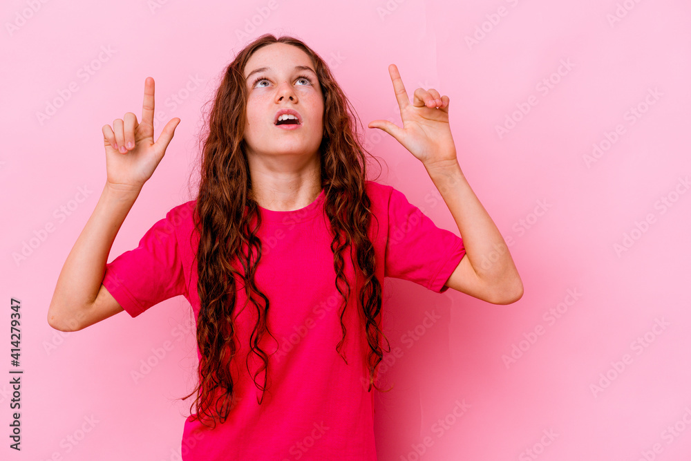 Little caucasian girl isolated on pink background pointing upside with opened mouth. Little caucasian girl isolated on pink background pointing upside with opened mouth.