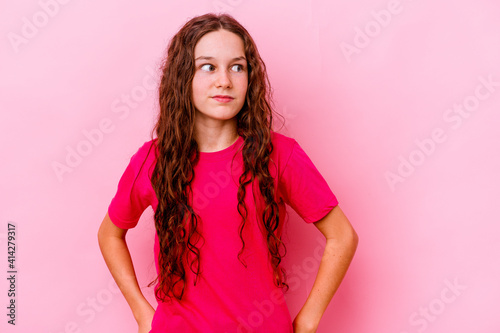 Little caucasian girl isolated on pink background confused, feels doubtful and unsure.