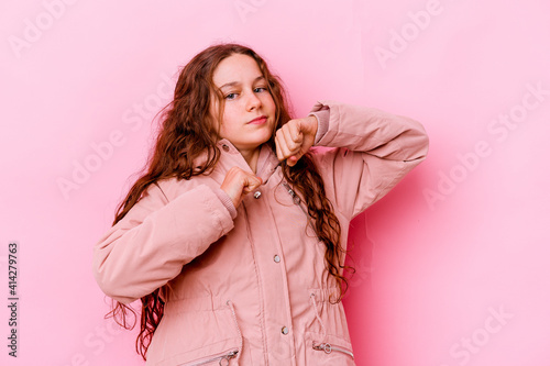 Little caucasian girl isolated on pink background throwing a punch, anger, fighting due to an argument, boxing.