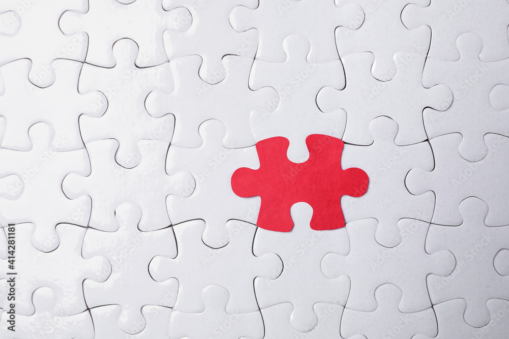 White jigsaw puzzles and red one as background, top view White jigsaw puzzles and red one as background, top view