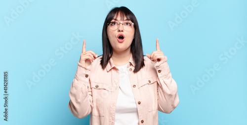 Φωτογραφία plus size pretty woman looking shocked, amazed and open mouthed, pointing upward