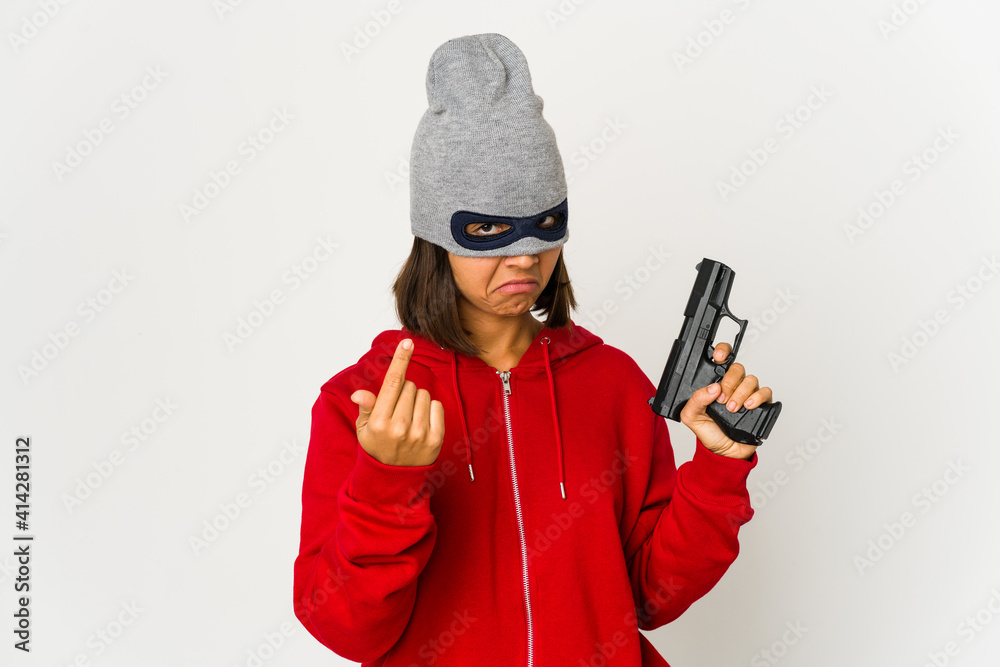 Young robber hispanic woman wearing a mask pointing with finger at you as if inviting come closer. Young robber hispanic woman wearing a mask pointing with finger at you as if inviting come closer.