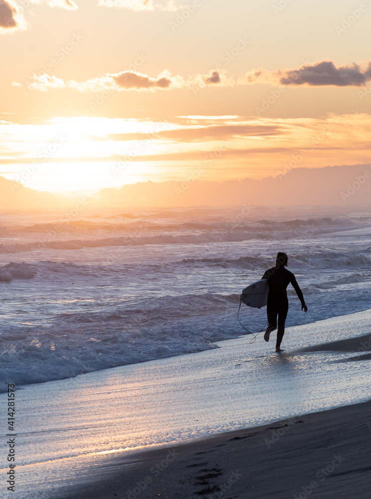 Surfer on the beach running during the sunset