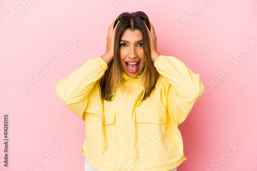 Young indian woman isolated on pink background screaming, very excited, passionate, satisfied with something.
