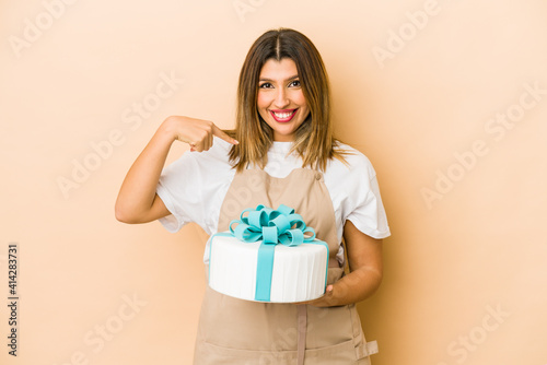 Young indian pastry chef woman isolated person pointing by hand to a shirt copy space, proud and confident