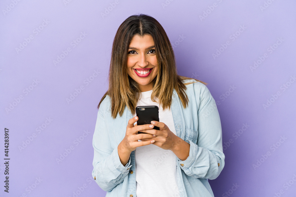 Young indian woman holding a phone isolated happy, smiling and cheerful. Young indian woman holding a phone isolated happy, smiling and cheerful.