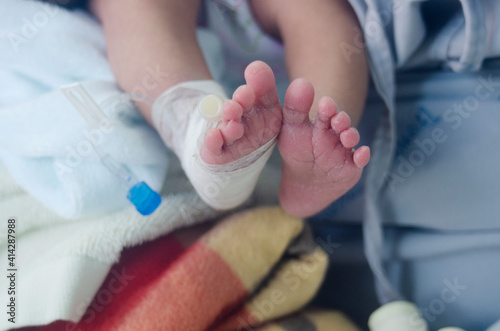 newborn baby's leg wrapped in a cotton swab and a needle for medication.