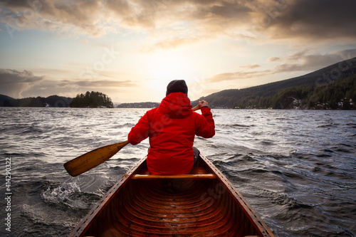 Fotografiet Adventure Man on a wooden canoe is paddling in the ocean