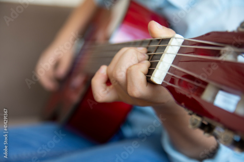 little boy playing guitar. close up of fingers and guitar frets