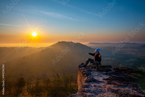 Asian tourist man sits and admires the sunrise on the cliff at Phu Dan Tong,Pho Sai district,Ubon ratchathani province,Thailand.