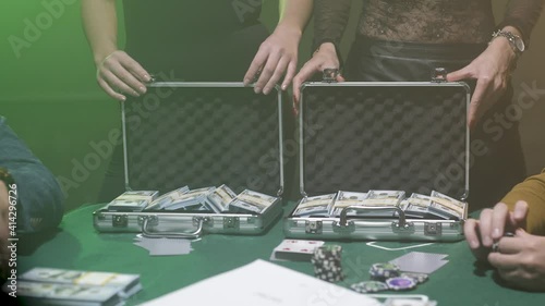 two girls open suitcases with money on the poker table