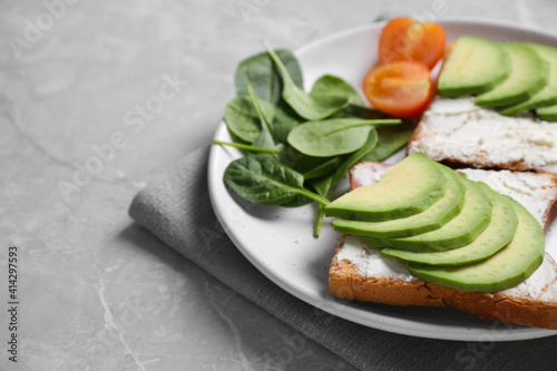 Sandwiches with avocado and spinach served on grey table, closeup. Space for text