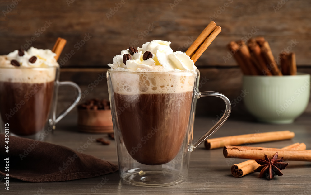 Delicious coffee with whipped cream and cinnamon on wooden table Delicious coffee with whipped cream and cinnamon on wooden table