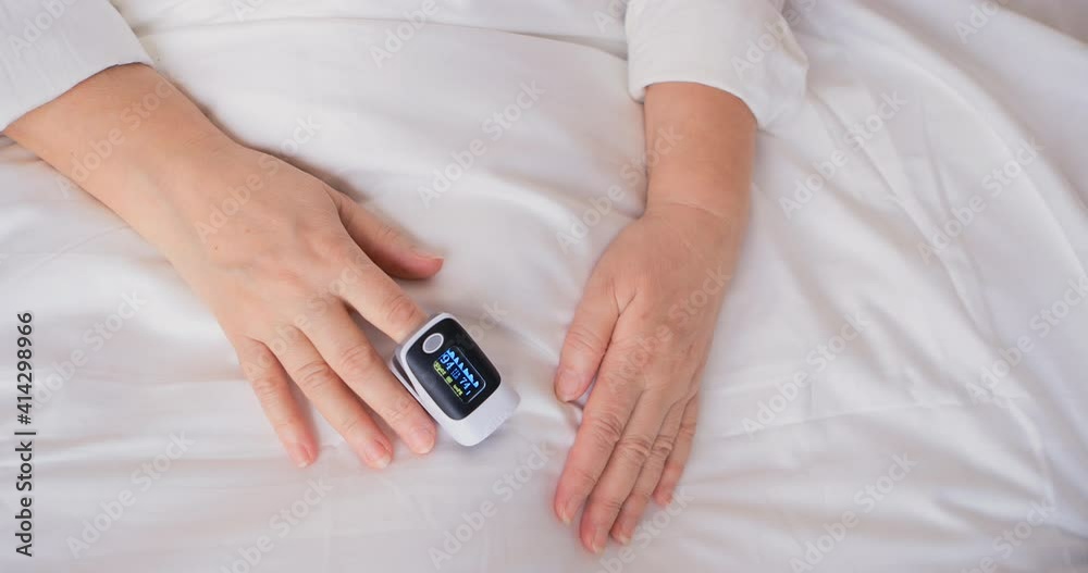 Retiree use finger digital device to measure oxygen saturation in blood and heart rate. Pulse