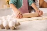 Mother and daughter rolling out dough in kitchen at home, closeup