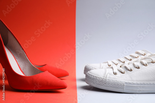 High heeled shoes and sneakers on color background