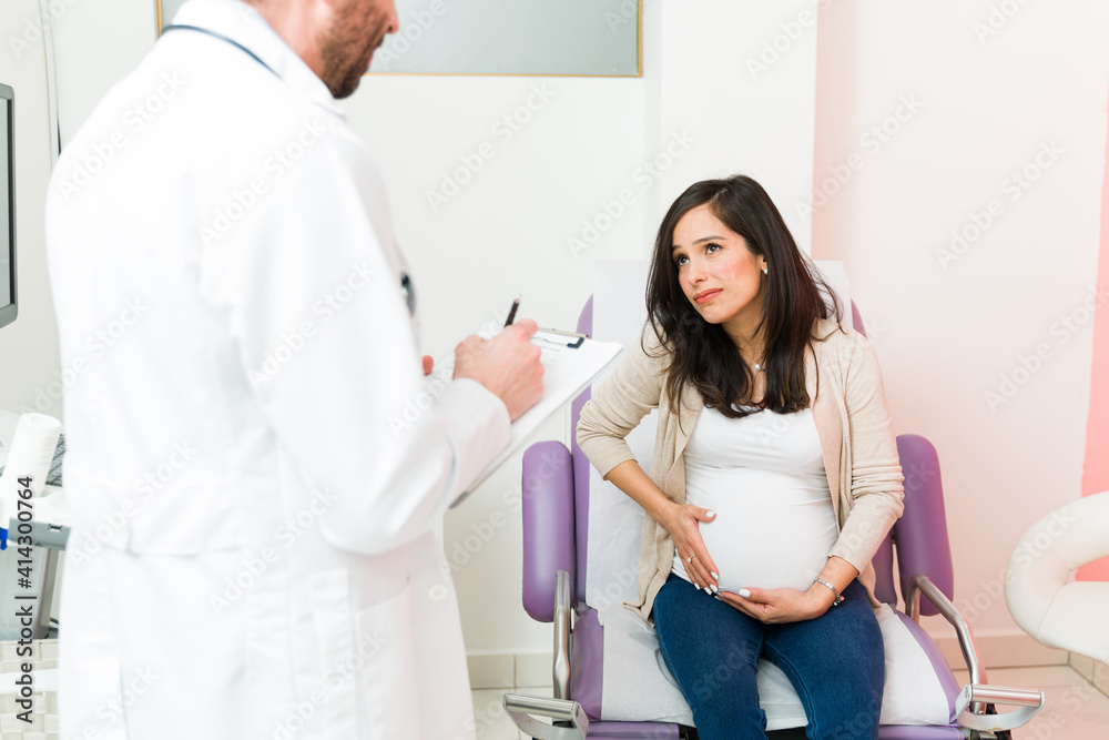 Sick expectant mother complaining about pain in the consulting room Sick expectant mother complaining about pain in the consulting room