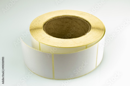 Babina of self-adhesive stickers on a white background. Self-adhesive white label roller for printing or manufacturing.