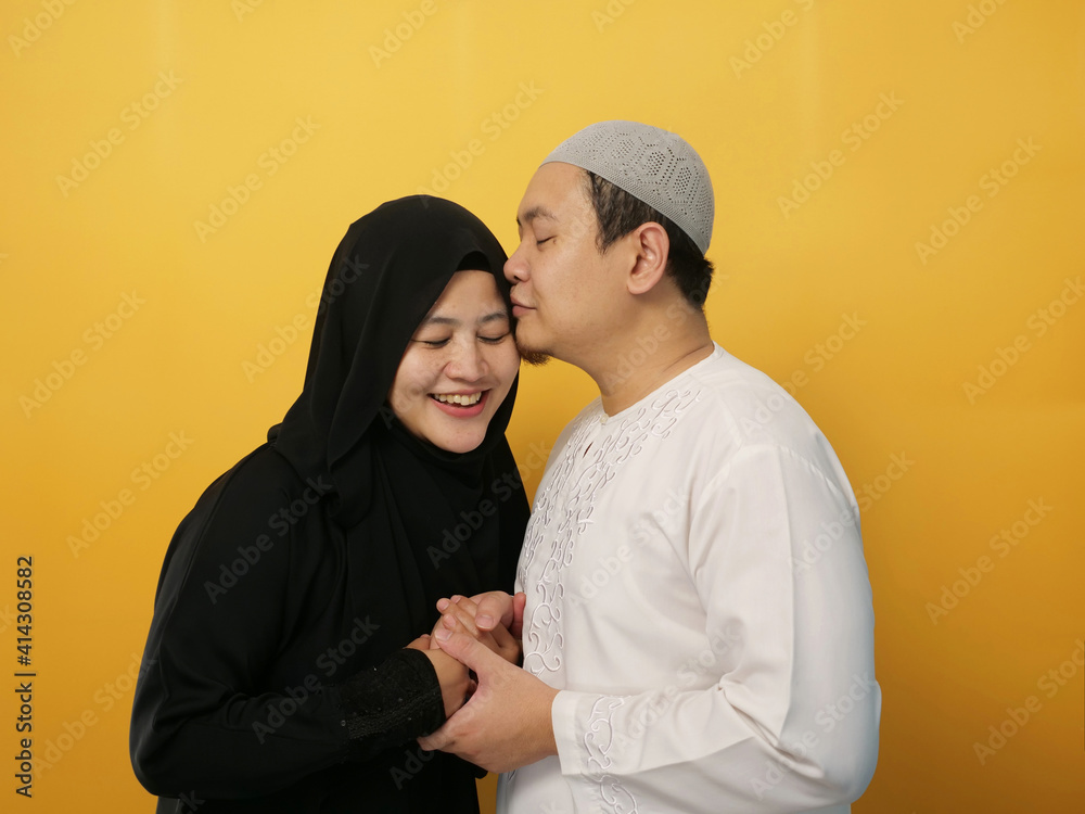 Portait of happy Asian muslim couple smiling, husband and wife hugging and kissing full of love, family