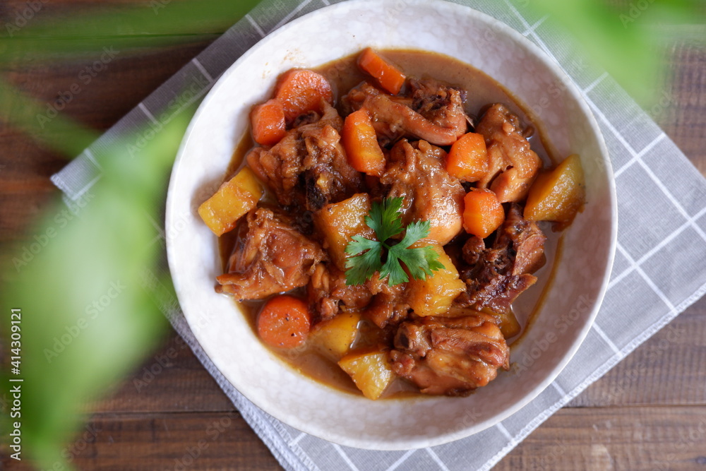 a plate of chicken stew with carrot and potato on a wooden table a plate of chicken stew with carrot and potato on a wooden table