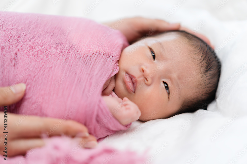 newborn baby wrap in blanket and parent hands on bed newborn baby wrap in blanket and parent hands on bed