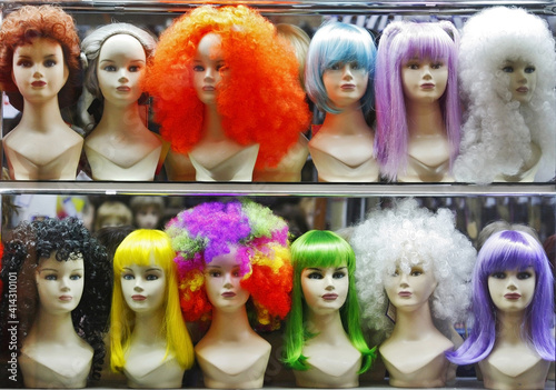 lots of multicolored female wigs on mannequin heads in a shop window  © wimages
