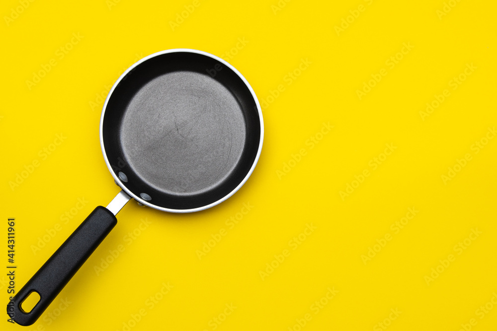 Black small pan on yellow background with copy space Black small pan on yellow background with copy space
