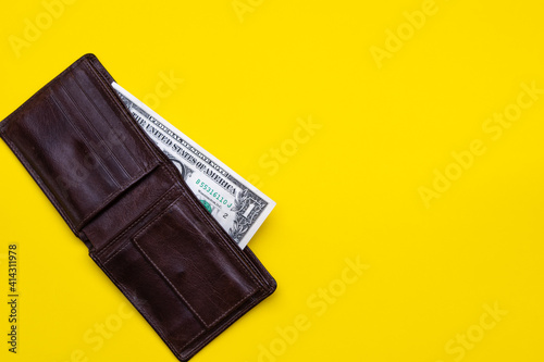 Dollar note in brown leather pocket on yellow blackground