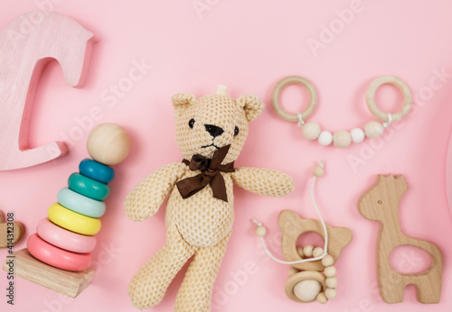 Wooden pyramid, toys, a horse on pastel pink background. Trendy cute baby first toys. Eco-friendly, plastic-free set of accessories for kids. Toys for kindergarten, preschool or daycare. Close up