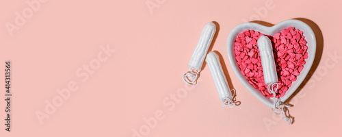 Medical female tampons and heart shape plate on pink background. Hygienic white organic tampon for women. Menstruation, means of protection. Stylish minimal concept, banner, flyer, hard shadow