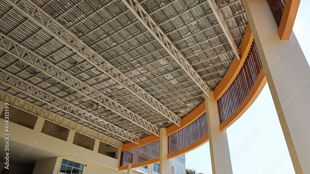 Obraz premium White metal roof structure. The eaves of the building are made of metal shingles with beams to filter between concrete columns in the bottom view. Selective focus