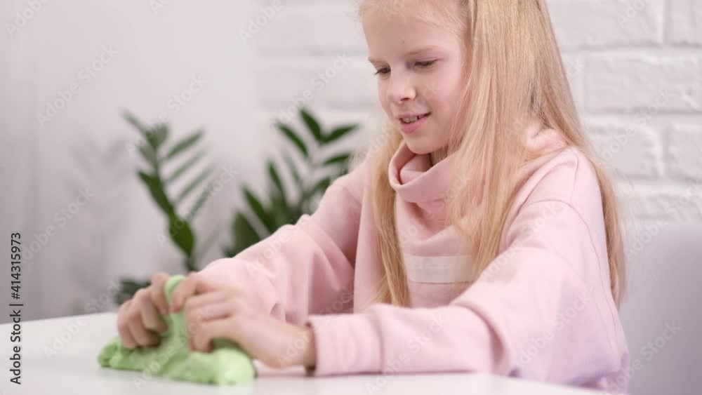 Hands with green slime close up. Girl stretching slime to the sides. kids hands playing slime toy. Making slime on white. Trendy liquid toy sticks to hands and fingers Slow motion. Hands with green slime close up. Girl stretching slime to the sides. kids hands playing slime toy. Making slime on white. Trendy liquid toy sticks to hands and fingers Slow motion.