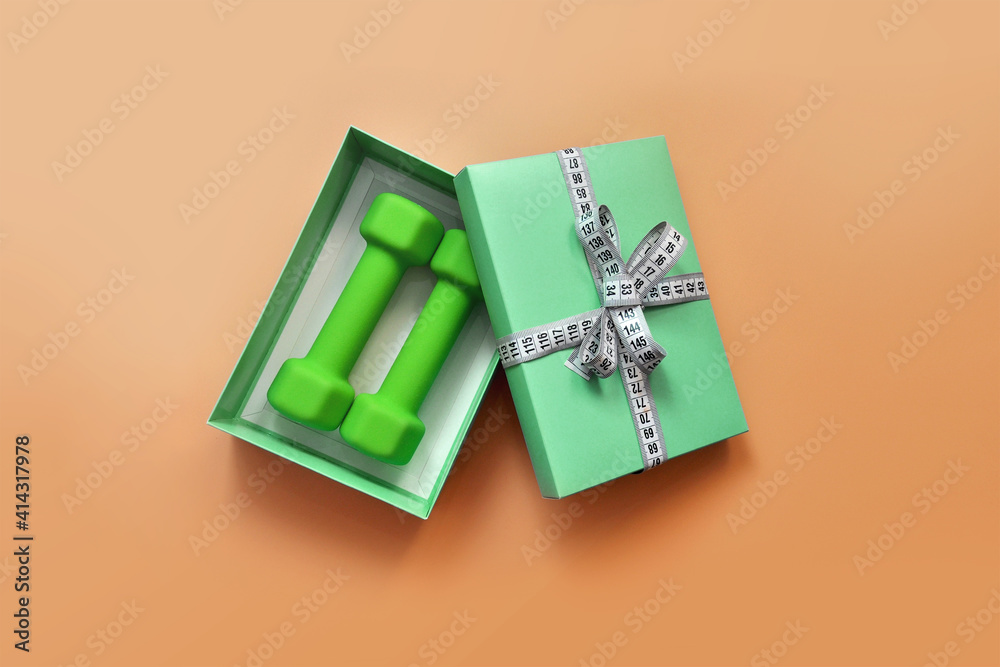 Green dumbbells in a gift box. Sports and a healthy lifestyle in the modern world Green dumbbells in a gift box. Sports and a healthy lifestyle in the modern world