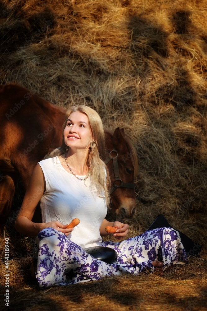 A girl holds a horse at a haystack with a musical instrument A girl holds a horse at a haystack with a musical instrument