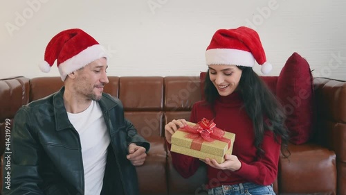 Man and woman couple in casual winter outfit with red hat giving gift box to surprise on holiday special day with happy and romantic emotion