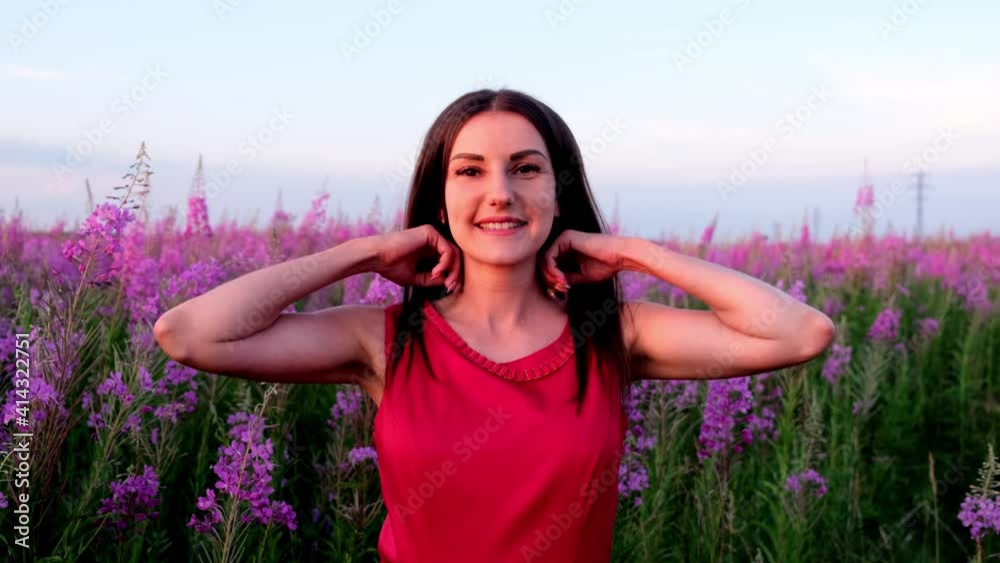 Portrait of a young brunette among the willow tea inflorescences at sunset. girl in high stems of fireweed on a bright sunny evening Portrait of a young brunette among the willow tea inflorescences at sunset. girl in high stems of fireweed on a bright sunny evening