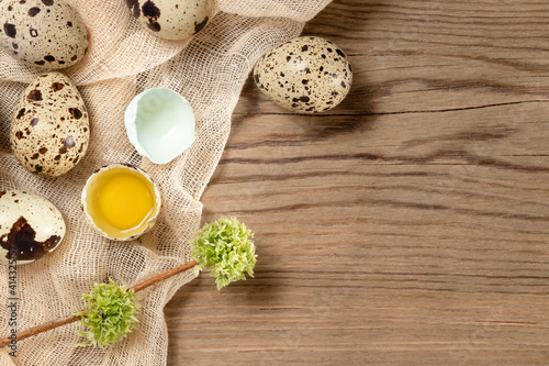 Composition of several quail eggs on decorative fabric on a wooden table, copy space, flatlay